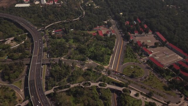 Aerial drone footage of Mexico City's Perif&eacute;rico Norte with traffic around a roundabout, lush vegetation, and Chapultepec Forest in the background.