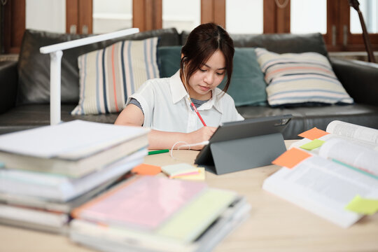 Asian teenage girl remote learning at home using a digital tablet.