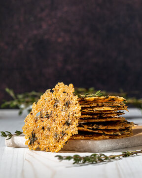 A stack of freshly baked parmesan thyme cheese crisps, against a dark background
