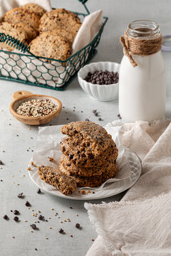 A stack of quinoa cookies with the top one broken in half, served with milk.