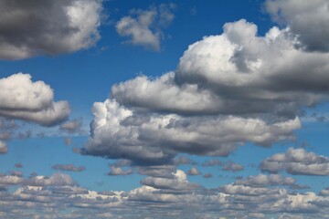 Soft white clouds drift across a clear blue sky, creating a calm, balanced composition with gentle movement and an open, peaceful atmosphere. © Liudmila