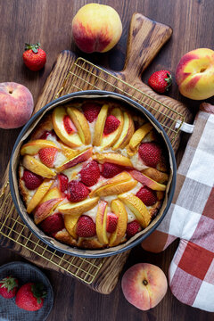 A baked strawberry peach cake on a cooling rack hot out of the oven. 