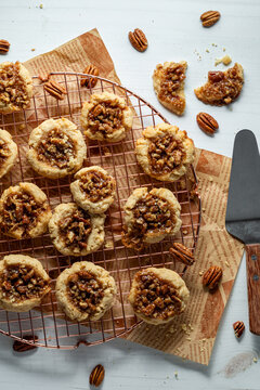 Delicious homemade pecan pie cookies on a cooling rack with one broken above.