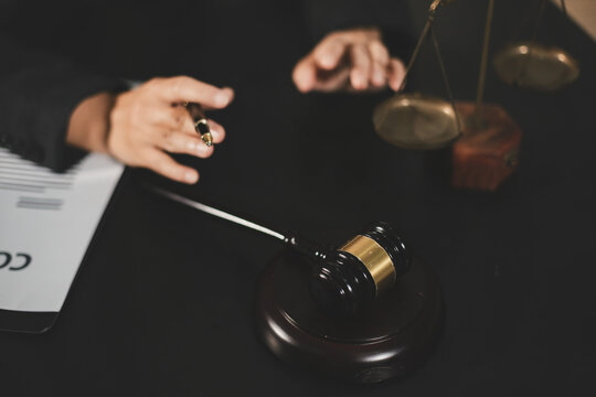 female lawyer in suit at workplace with laptop, gavel and femida in office