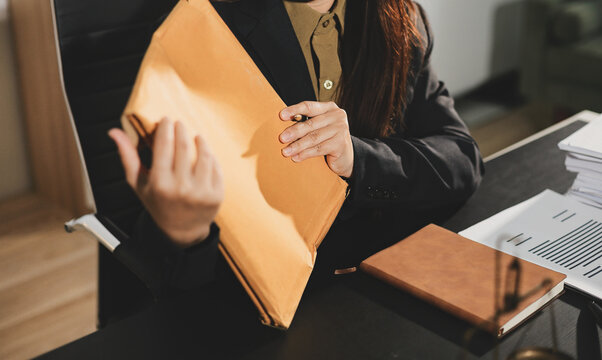 female lawyer in suit at workplace with laptop, gavel and femida in office