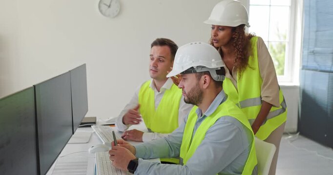 Engineers team in controlroom monitoring technology operations. They analyze dashboards on monitors, discuss safety protocols, and coordinate industrial tasks. Clear concept of data analysis.