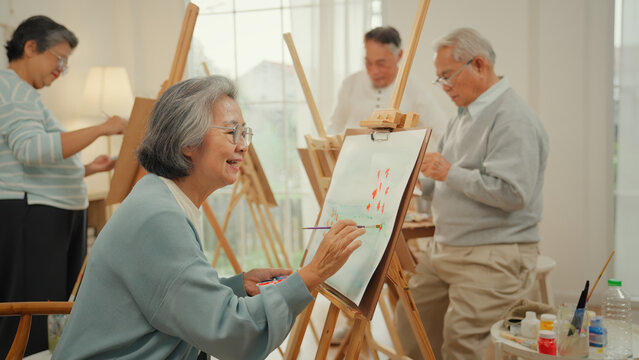 Senior Asian group participating in art therapy painting class at a nursing home, with caregiver support for elderly women and patients, promoting retirement care, wellness and creativity