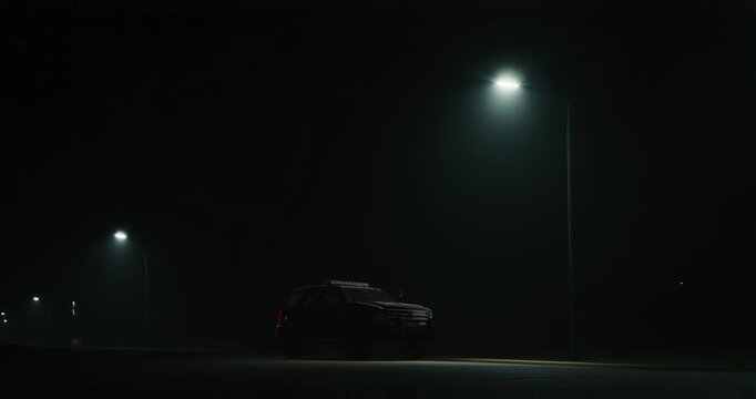 Parked emergency vehicle with flashing beacon under streetlights at night