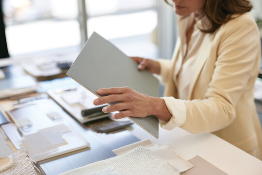 A designer thoughtfully reviews fabric samples, showcasing the importance of material selection in creating an appealing interior space while working professionally.