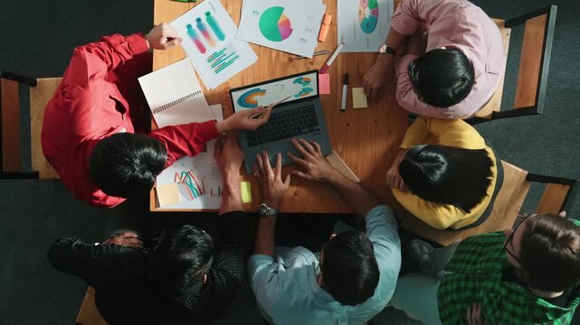 Top view of business team looking at laptop and analyzing chart. Close up of diverse group working on computer and reading financial report. Group of people explain idea at meeting. Convocation.