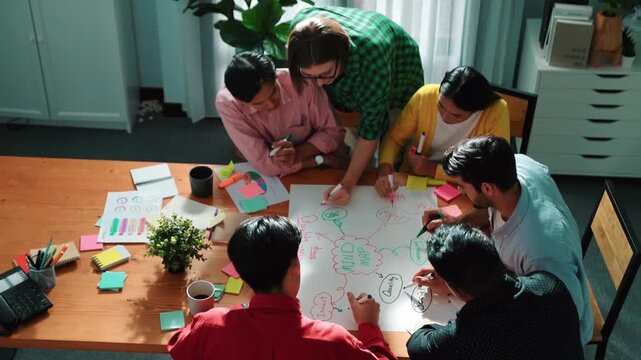 Top down view of smart business team in casual cloth brainstorming marketing idea and writing mind map together. Professional creative people using mind map to share and exchange idea. Convocation.