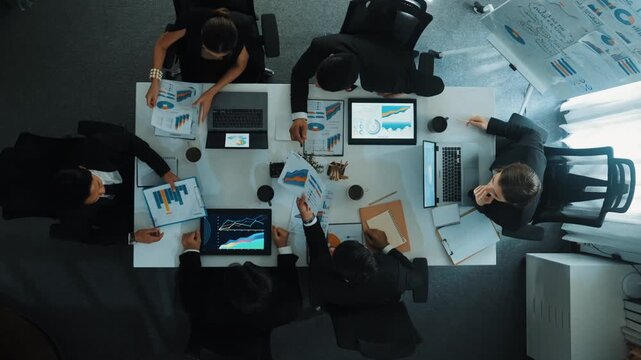 Top view of businesswoman sit at seat and start to analyze stock market data with diverse business team at meeting table with marketing chart document and tablet display financial report. Directorate.