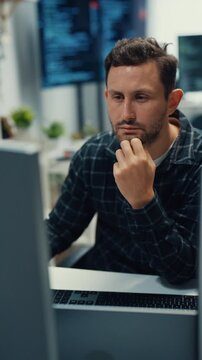 Vertical Screen : Young Caucasian male programmer writes code using multiple screens in home office. AI development, cybersecurity, network database system, software engineering, remote tech startup.