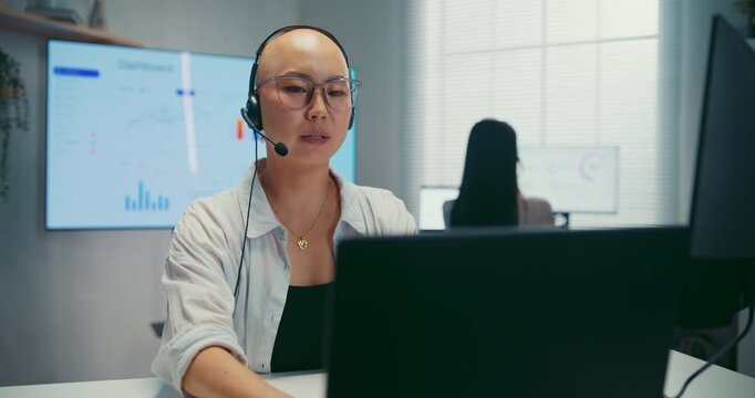 Young Asian female agent talking on phone headset consulting client online in call center office. Corporate customer service, technical support, remote tech operator, business team help desk concept.