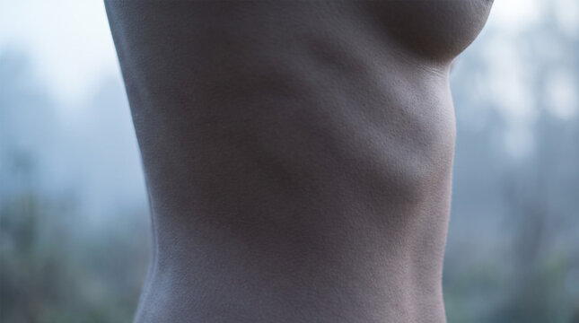 Side view of slender female ribcage and waist in cool light