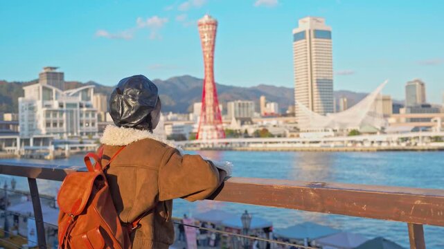 Young happy woman tourist enjoying the beautiful city landscape while traveling in Kobe port, Japan