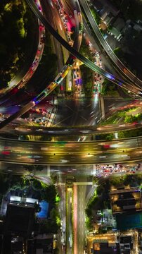 Night timelapse aerial view of busy highway interchange in Jakarta, Indonesia. Light trails from cars, multilayer roads, and urban traffic system in motion.