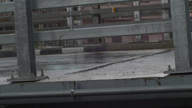Blurred Motorcycle Speeding Under Wet Guardrail Bridge, Caution on Slippery Rain-Soaked Road Concept