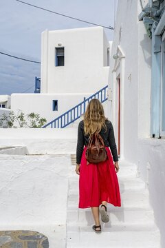 Young woman with red skirt in the alleys of Ano Mera, Cycladic white houses, Ano Mera, Mykonos, Cyclades, Greece