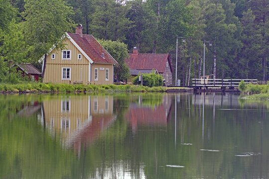 Red roof houses along a canal with reflecting water and wooded surroundings, Sj&ouml;torp, G&ouml;ta Canal, G&ouml;taleden, V&auml;stra G&ouml;talands l&auml;n, Sweden
