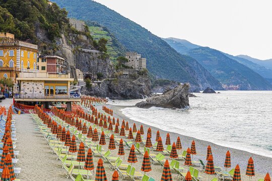 Sun loungers and parasols, boulders on the beach di Fegina, behind the Torre Aurora Mare, Monterosso al Mare, Cinque Terre, Ligurian Coast, Liguria, Italy