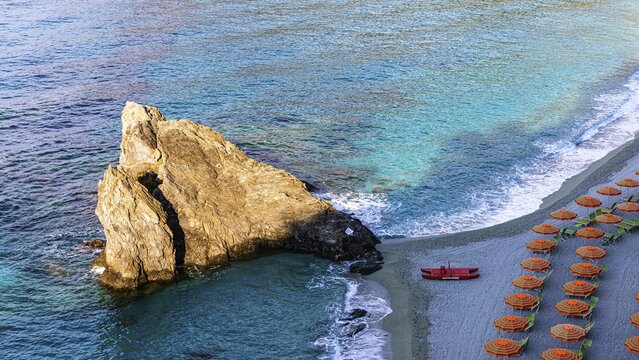 Sunbeds, parasols and red lifeboat, boulders on the beach di Fegina, Monterosso al Mare, Cinque Terre, Ligurian Coast, Liguria, Italy