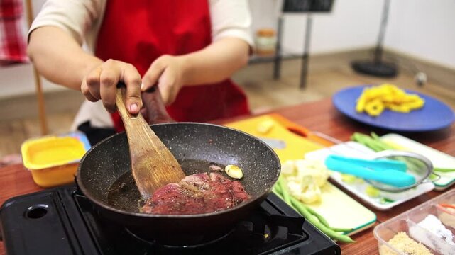 Home cook flipping searing beef steak in hot skillet with butter and garlic