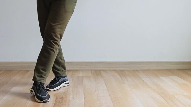 Low angle shot of person practicing fast footwork and shuffle drills on wooden floor indoors