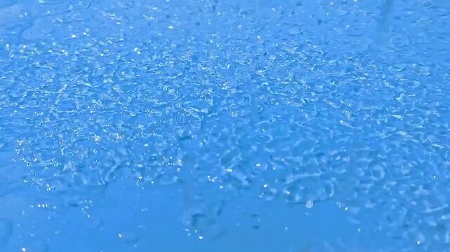 青い背景に激しく降り出す雨粒と雫のクローズアップイメージ