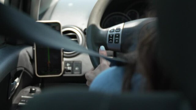 Focused Driving Woman Adjusting Car Stereo Controls While Using Smartphone GPS Navigation