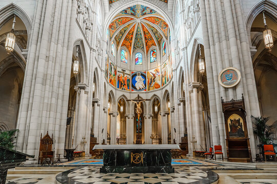 Illuminated apse with painted dome and crucifix in Almudena Cathedral, Madrid