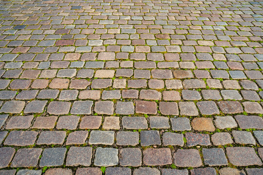 Cobblestone pavement forms an old street. Cobblestone pavement features weathered stone texture. Urban road texture frames cobblestone pavement. Historic road uses cobblestone pavement.