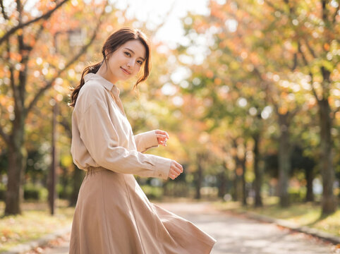 秋の並木道を散策しながら振り返る笑顔の女性