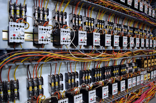 Industrial electrical control panel with complex wiring and circuit breakers in a factory.