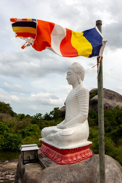 A Buddhist flag flies adjacent to a statue of Buddha at Madya Mandalaya near Panama in Sri Lanka which was originally established as the Hermitage of Kudumbigala by King Kwan Tissa (BC 210- 161).