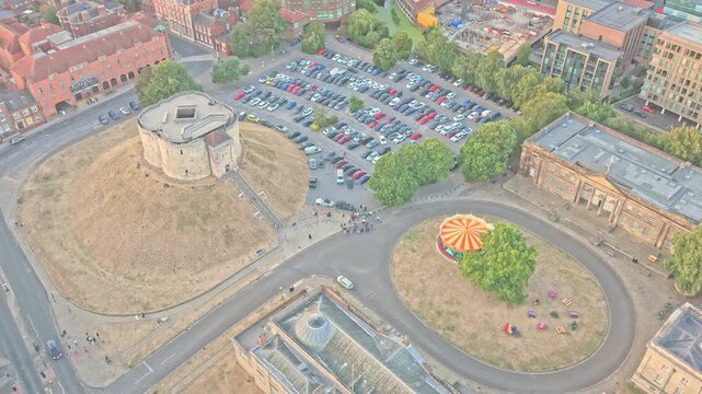 Clifford's Tower rises above the Eye of York in England, surrounded by Castle Museum, Crown Court, Tower Street and the Castle precinct, drone descent push-in.