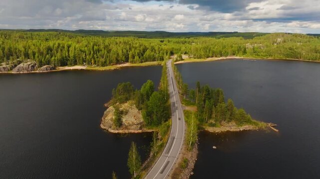 Aerial view backwards over motorbikes driving on scenic Lietvesi road n Finland