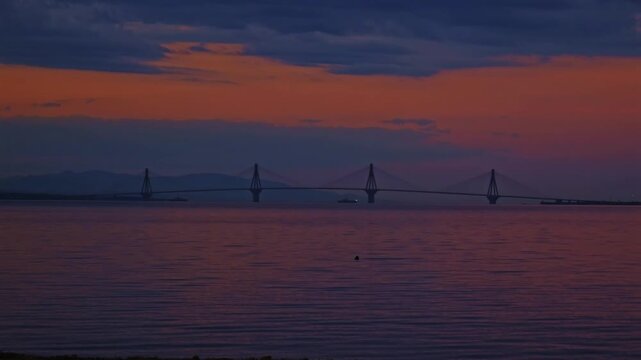 Time-lapse shot of dawn breaking over the Rio-Antirrio cable-stayed bridge spanning the Gulf of Corinth, connecting the Peloponnese to mainland Greece.