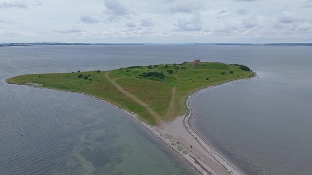 Drone orbit above the historic Kalo Castle Ruins on a cloudy day, showcasing the medieval fortress and the scenic coastal landscape of Eastern Jutland, Denmark.