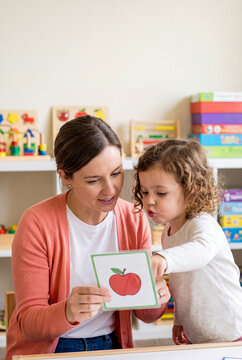 Speech Therapist Teaching Toddler Girl with Flashcard in Classroom