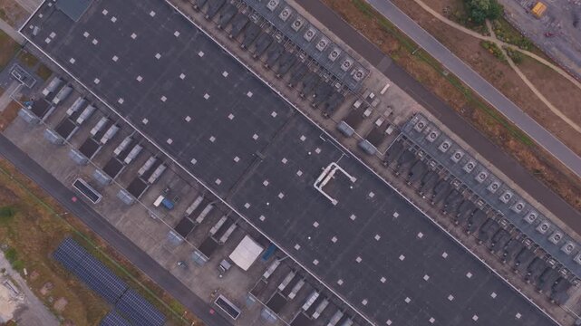 Overhead drone footage of a large scale data center facility with numerous rooftop cooling units, critical for ai and cloud computing infrastructure