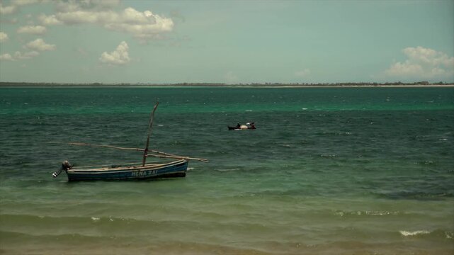 traditional wooden dhow boat floating in shallow green-blue waters off the Mozambique coast. Warm sunlight, distant horizon, and peaceful tropical African seascape.