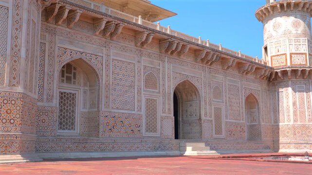 Low angle shot showing ornate white marble facade with detailed pietra dura stone inlay and archways at Tomb of Itimad-ud-Daulah in Agra, Uttar Pradesh, India