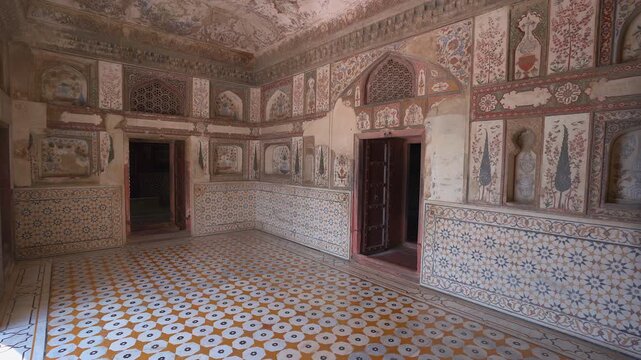 Slow pan of decorated royal room featuring intricate floral wall murals and geometric tile patterns inside Amer Fort in Jaipur, Rajasthan, India.