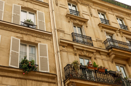 Classic haussmannian apartment building facade in paris, france, with ornate balconies and window shutters
