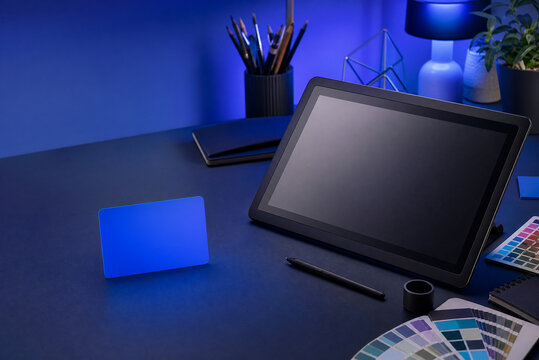 Professional digital drawing tablet on designer desk, creative workspace with blue neon lighting, graphic artist studio equipment