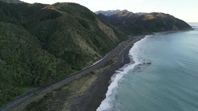 Pacific Ocean road aerial view near Ohau Point New Zealand showcases a rugged rocky coast with powerful waves, beautiful island scenery and dramatic mountains for travel tourism 