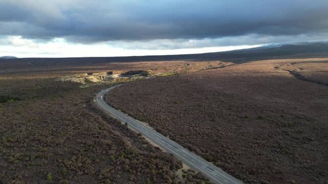 Aerial view of Rangipo desert landscape in New Zealand with a long road crossing the remote volcanic terrain surrounded by dramatic scenery for travel and tourism