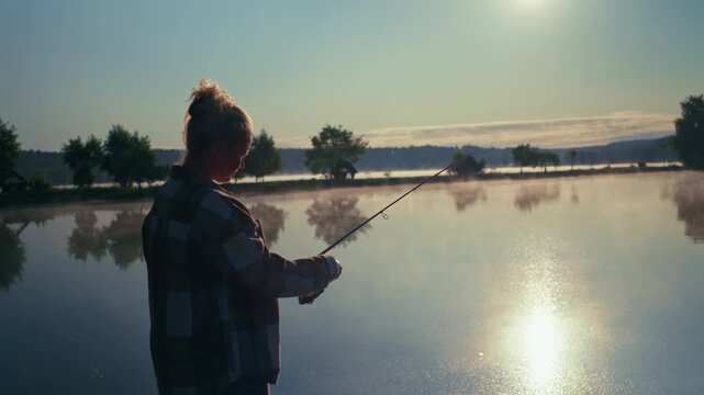 Female angler casting a spinning rod across a calm lake at sunrise surrounded by beautiful natural scenery and peaceful outdoor lifestyle moments
