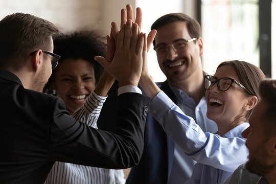 Happy diverse business team celebrating success with a high five in a modern office setting